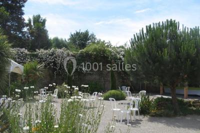 Allée ombragée avec banc en bois, hortensias en fleurs et panneaux directionnels près d'un arbre.