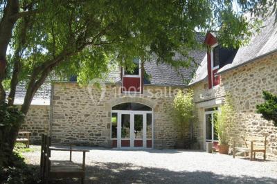 Allée ombragée avec banc en bois, hortensias en fleurs et panneaux directionnels près d'un arbre.
