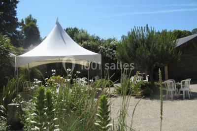 Allée ombragée avec banc en bois, hortensias en fleurs et panneaux directionnels près d'un arbre.