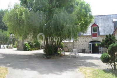 Allée ombragée avec banc en bois, hortensias en fleurs et panneaux directionnels près d'un arbre.