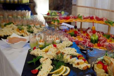 Grand jardin avec pelouse, arbres alignés et une structure couverte avec des tables et chaises blanches.