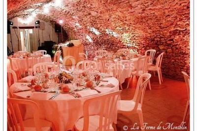 Salle voûtée en pierre avec éclairage rouge, tables basses, poufs et narguilés disposés dans une ambiance orientale.