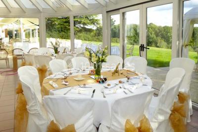 Salle voûtée en pierre avec éclairage rouge, tables basses, poufs et narguilés disposés dans une ambiance orientale.