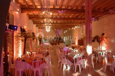 Salle voûtée en pierre avec éclairage rouge, tables basses, poufs et narguilés disposés dans une ambiance orientale.