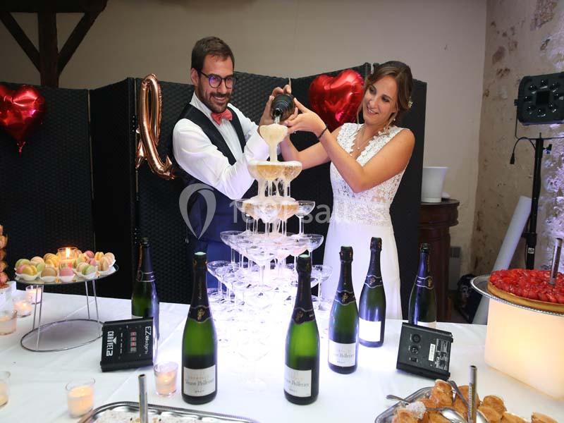 Un couple verse du champagne dans une pyramide de coupes lors d'une réception festive.