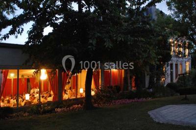 Salle de réception éclairée par des lumières violettes, avec un bar et des tables dans un décor chaleureux.