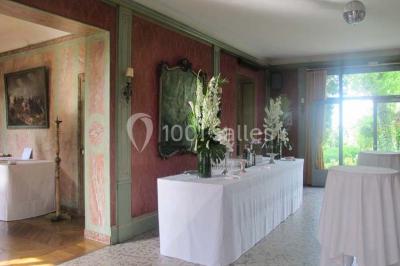 Salle de réception éclairée par des lumières violettes, avec un bar et des tables dans un décor chaleureux.