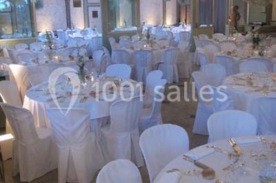 Salle de réception éclairée par des lumières violettes, avec un bar et des tables dans un décor chaleureux.