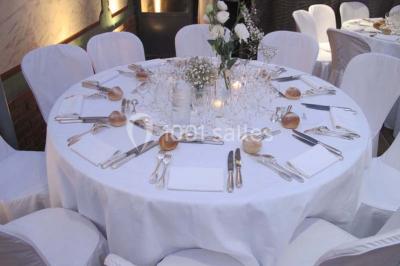Salle de réception éclairée par des lumières violettes, avec un bar et des tables dans un décor chaleureux.