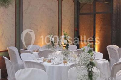 Salle de réception éclairée par des lumières violettes, avec un bar et des tables dans un décor chaleureux.