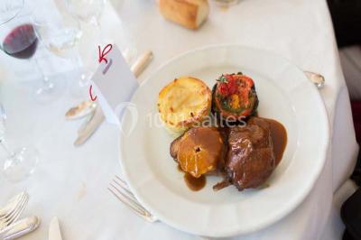 Salle de réception éclairée par des lumières violettes, avec un bar et des tables dans un décor chaleureux.