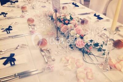 Salle de réception éclairée par des lumières violettes, avec un bar et des tables dans un décor chaleureux.