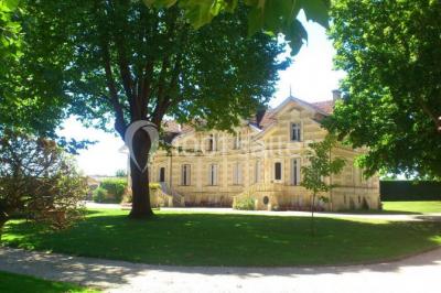 Salle à manger élégante avec table dressée, bouquet de fleurs au centre, grande fenêtre ouverte sur un jardin verdoyant.