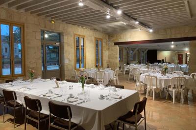 Salle à manger élégante avec table dressée, bouquet de fleurs au centre, grande fenêtre ouverte sur un jardin verdoyant.
