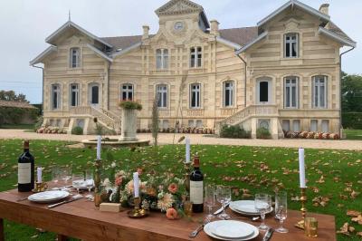 Salle à manger élégante avec table dressée, bouquet de fleurs au centre, grande fenêtre ouverte sur un jardin verdoyant.