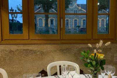 Salle à manger élégante avec table dressée, bouquet de fleurs au centre, grande fenêtre ouverte sur un jardin verdoyant.