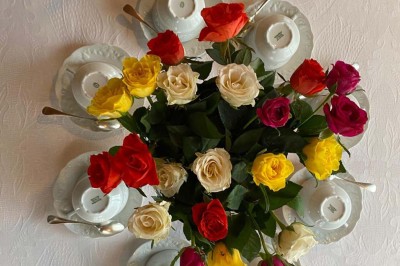 Grande table dressée avec nappes blanches, chaises blanches et chandeliers, dans une salle en pierre avec cheminée.