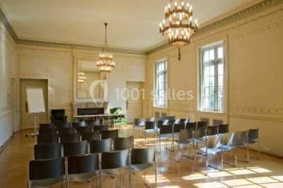 Pelouse avec des personnes assises ou allongées devant un grand bâtiment historique entouré d'arbres.