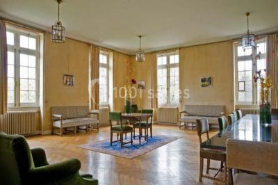 Pelouse avec des personnes assises ou allongées devant un grand bâtiment historique entouré d'arbres.