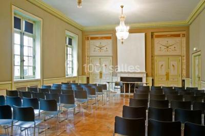 Pelouse avec des personnes assises ou allongées devant un grand bâtiment historique entouré d'arbres.