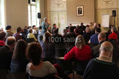 Pelouse avec des personnes assises ou allongées devant un grand bâtiment historique entouré d'arbres.