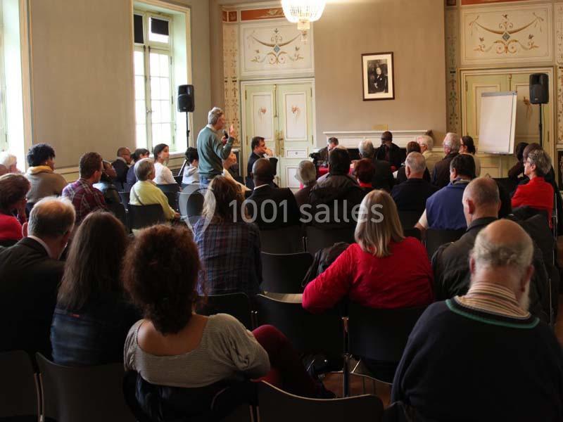 Un groupe de personnes assises dans une salle lors d'une réunion ou d'une présentation avec un intervenant debout.