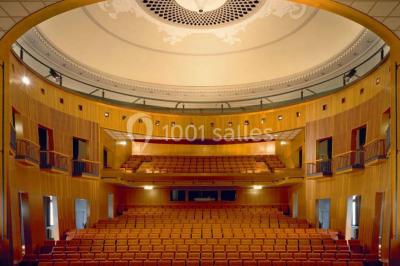 Pelouse avec des personnes assises ou allongées devant un grand bâtiment historique entouré d'arbres.