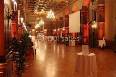 Pelouse avec des personnes assises ou allongées devant un grand bâtiment historique entouré d'arbres.