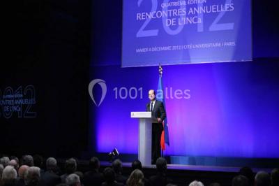 Pelouse avec des personnes assises ou allongées devant un grand bâtiment historique entouré d'arbres.