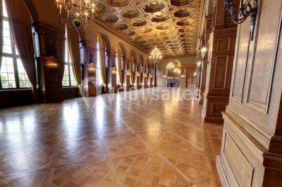 Pelouse avec des personnes assises ou allongées devant un grand bâtiment historique entouré d'arbres.