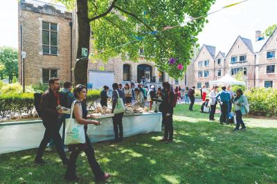 Pelouse avec des personnes assises ou allongées devant un grand bâtiment historique entouré d'arbres.