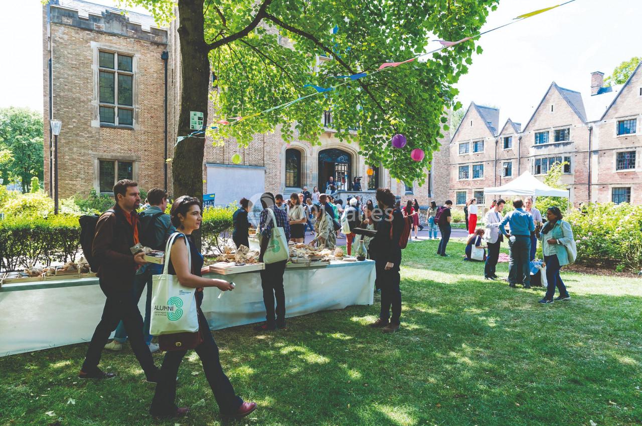 Des personnes rassemblées dans un jardin, discutant et se servant à des tables lors d'un événement en plein air.