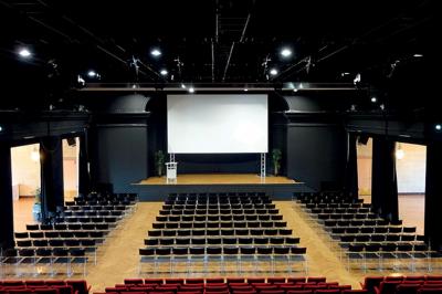 Pelouse avec des personnes assises ou allongées devant un grand bâtiment historique entouré d'arbres.