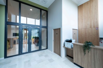 Façade d'un grand bâtiment historique avec un toit mansardé, entouré d'une pelouse où des personnes se détendent.