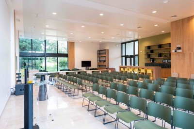 Façade d'un grand bâtiment historique avec un toit mansardé, entouré d'une pelouse où des personnes se détendent.