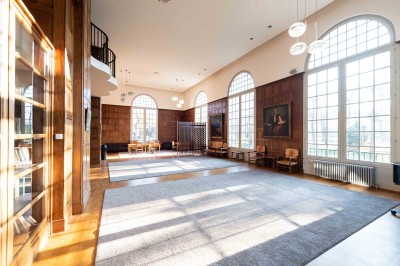 Façade d'un grand bâtiment historique avec un toit mansardé, entouré d'une pelouse où des personnes se détendent.