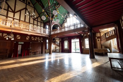 Façade d'un grand bâtiment historique avec un toit mansardé, entouré d'une pelouse où des personnes se détendent.