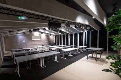 Façade d'un grand bâtiment historique avec un toit mansardé, entouré d'une pelouse où des personnes se détendent.