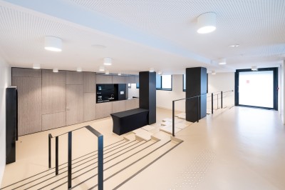 Façade d'un grand bâtiment historique avec un toit mansardé, entouré d'une pelouse où des personnes se détendent.