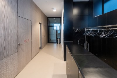 Façade d'un grand bâtiment historique avec un toit mansardé, entouré d'une pelouse où des personnes se détendent.