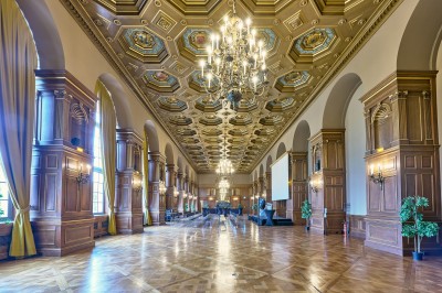 Façade d'un grand bâtiment historique avec un toit mansardé, entouré d'une pelouse où des personnes se détendent.