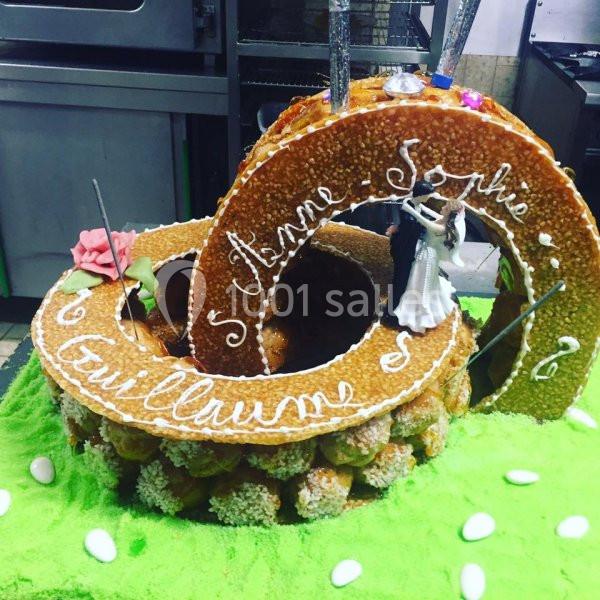 Pièce montée en choux caramélisés décorée avec des figurines de mariés et des inscriptions personnalisées.