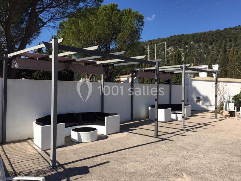 Pergolas modernes avec salons extérieurs circulaires et tables basses, installés sur une terrasse ensoleillée.