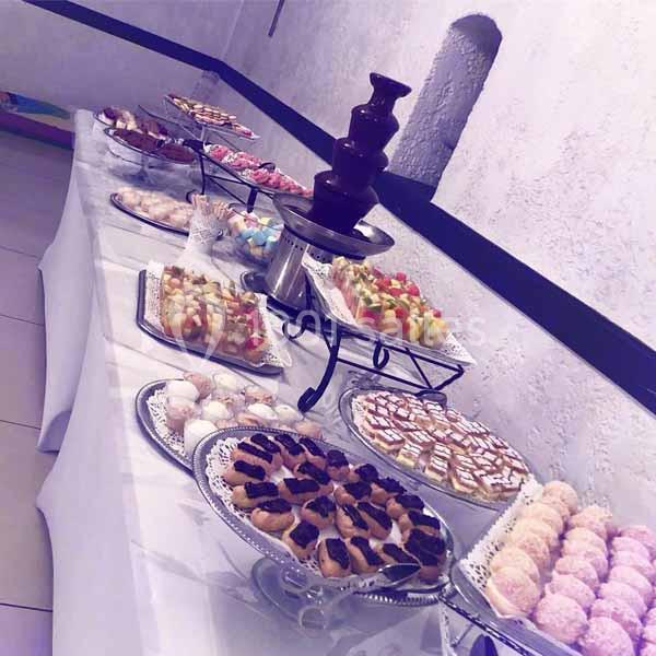 Table garnie de desserts variés, incluant une fontaine de chocolat et des assortiments de pâtisseries et fruits.
