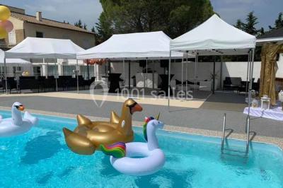 Bouées en forme de cygne et licorne flottant dans une piscine, avec des tentes blanches en arrière-plan.