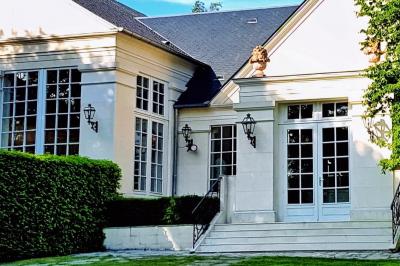 Couronne de fleurs blanches et roses suspendue à un arbre sous la lumière du soleil dans un jardin verdoyant.