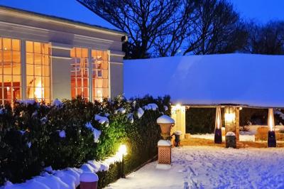 Couronne de fleurs blanches et roses suspendue à un arbre sous la lumière du soleil dans un jardin verdoyant.