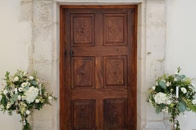 Couronne de fleurs blanches et roses suspendue à un arbre sous la lumière du soleil dans un jardin verdoyant.