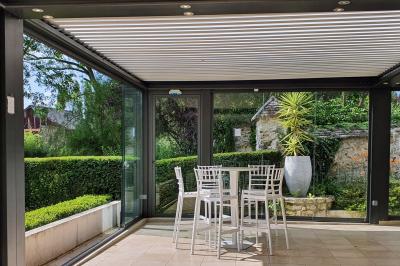 Couronne de fleurs blanches et roses suspendue à un arbre sous la lumière du soleil dans un jardin verdoyant.