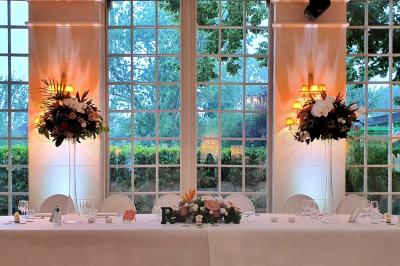 Couronne de fleurs blanches et roses suspendue à un arbre sous la lumière du soleil dans un jardin verdoyant.